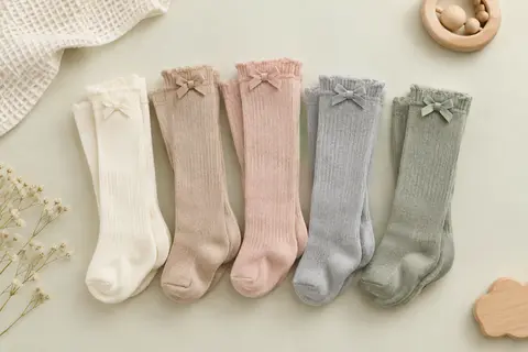 Cinq paires de chaussettes hautes pour bébé avec un nœud décoratif, pliées sur un fond clair.