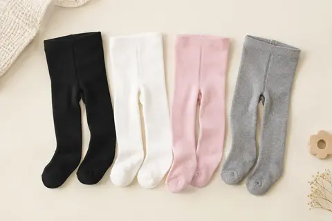Quatre paires de collants opaques pour bébé, en noir, blanc, rose et gris, présentées à plat.